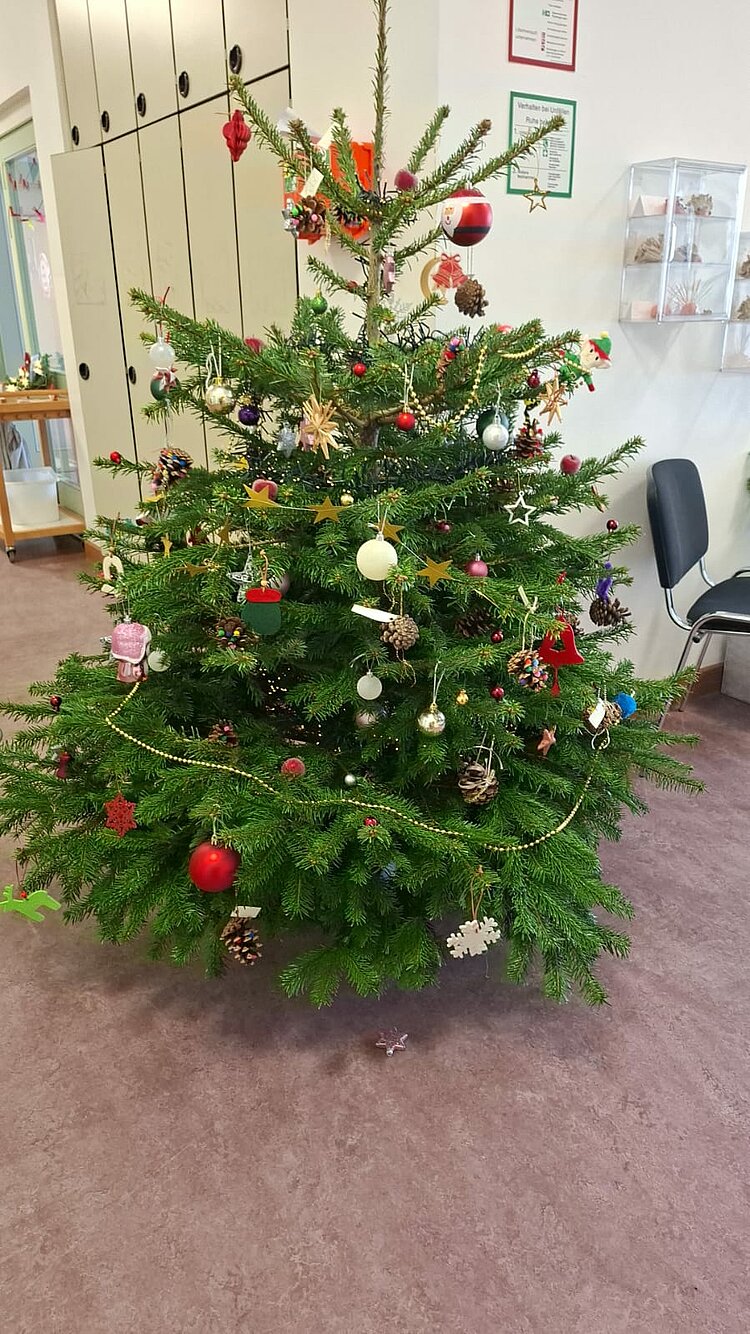 Ein bunt geschmückter Weihnachtsbaum im hellen Eingangsbereich einer KITA.