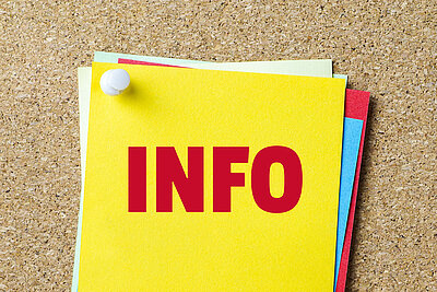 Die Aufschrift "Info" in großen roten Lettern steht auf einem gelben Zettel, der mit andern bunten Zetteln auf einer Pinwand angepinnt ist.